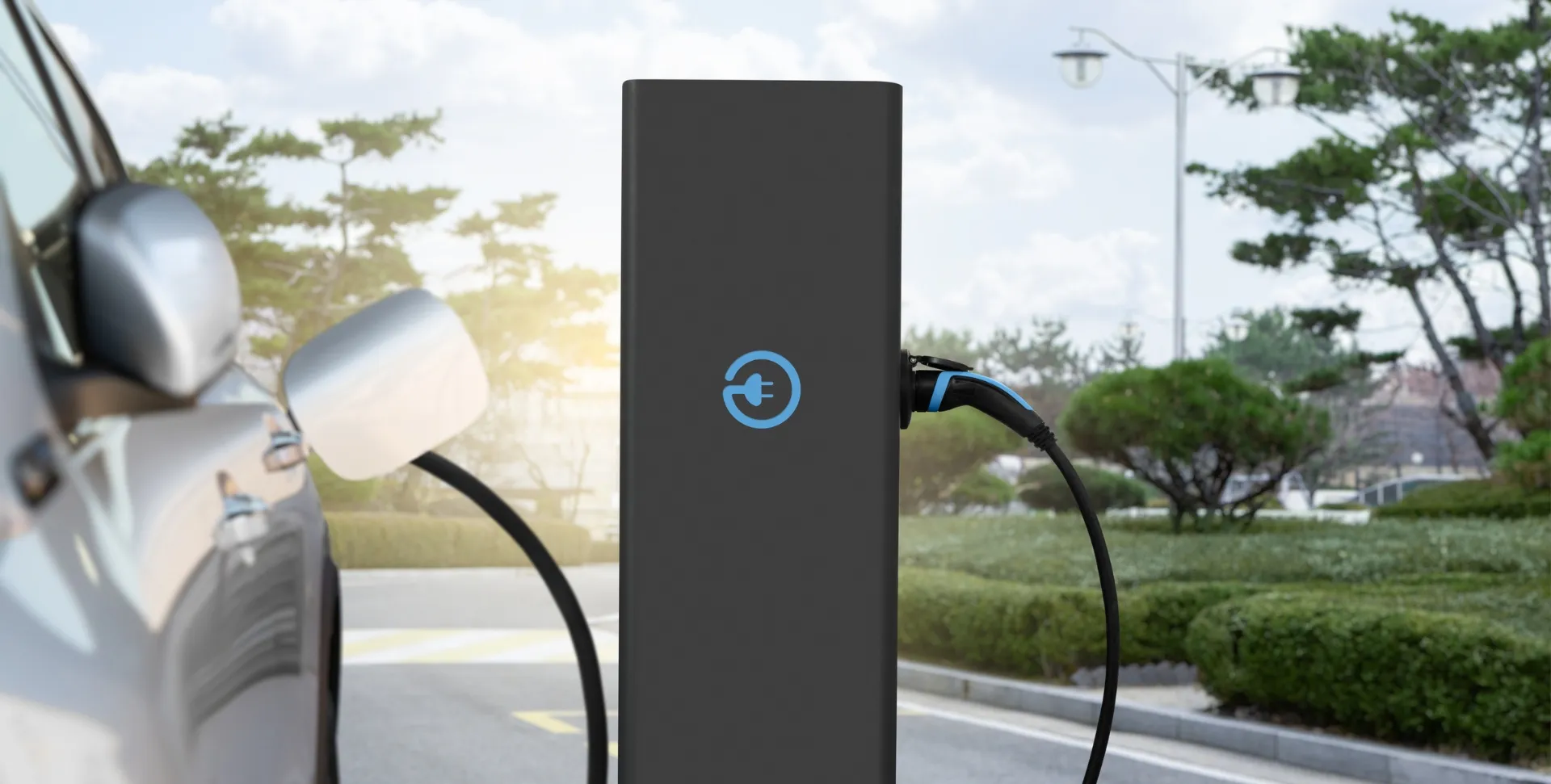 Ladesäule für Elektrofahrzeuge mit angeschlossenem Ladekabel auf einem Firmenparkplatz